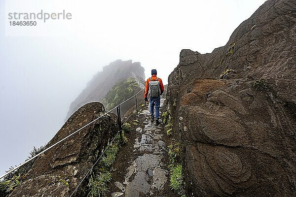 Wanderer im Nebel  Pico Arieiro zum Pico Ruivo Wanderung  schmaler ausgesetzter Wanderweg an Felsenklippe  Zentralgebirge Madeiras  Madeira  Portugal  Europa