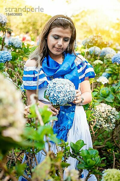 Schöne Nicaraguanerin in Volkstracht hält Blumen in einer Gärtnerei. Porträt eines Mädchens in traditioneller mittelamerikanischer Volkstracht  das in einer Gärtnerei Blumen hält. Nicaraguanische Volkstracht