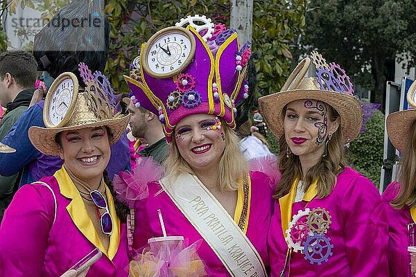 Drei maskierte  lächelnde Mädchen in rosafarbener Kleidung mit Uhr-Hut beim Karneval in der Stadt Rijeka  Kroatien  Europa