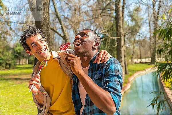 Ein paar multiethnische Männer essen einen Lutscher  lgbt Konzept  haben Spaß und lächeln