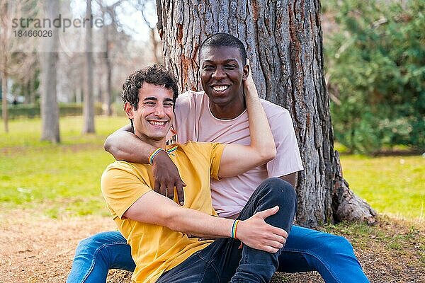 Paar multiethnische Männer in einem Park  lgbt Konzept  sitzen zusammen einen Baum in einer romantischen Pose