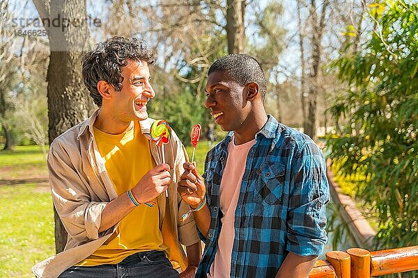 Multiethnisches männliches Paar isst einen Lutscher  lgbt Konzept  lächelnd