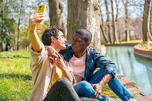 Selfie eines multiethnischen schwulen männlichen Paares  das sich im Park an einem Fluss unterhält  lgbt Konzept