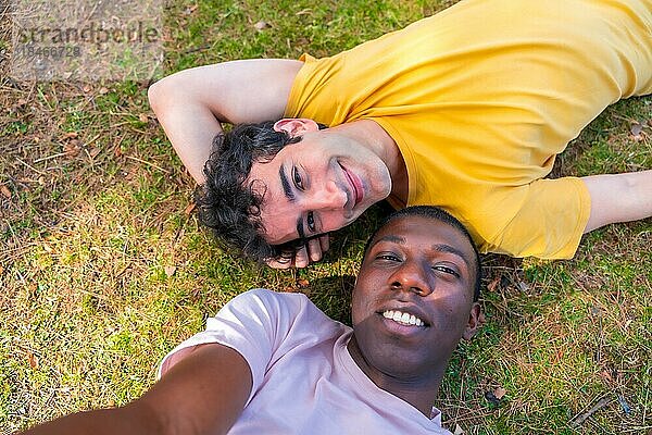 Paar multiethnische Männer in einem Park  lgbt Konzept  auf dem Gras liegend  ein Selfie machen