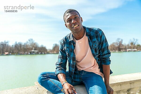 Porträt eines schwarzen ethnischen Mannes im Sommer an einem Stadtsee  der seinen Urlaub genießt