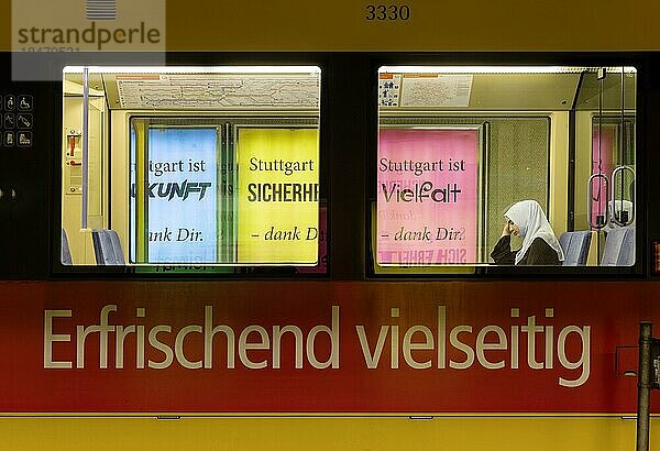 Die Stadt wirbt auf Plakaten für Vielfalt. Eine Muslimin mit Kopftuch sitzt in der Stadtbahn  die ein vielseitiges Produkt bewirbt  Stuttgart  Baden-Württemberg  Deutschland  Europa