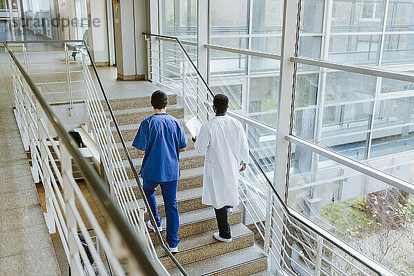Hohe Winkel Ansicht der männlichen Arzt und Krankenschwester diskutieren  während die Bewegung auf der Treppe im Krankenhaus