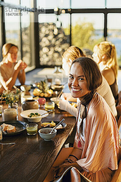 Porträt einer glücklichen Frau  die mit dem Frühstück auf dem Esstisch eines Rückzugszentrums sitzt