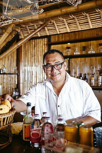 Porträt eines lächelnden Barkeepers mit Brille am Tresen in einem Ferienort