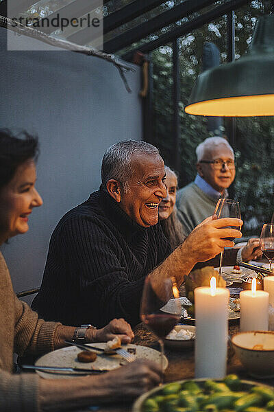 Glücklicher reifer Mann genießt mit Freunden im Ruhestand während einer Dinnerparty
