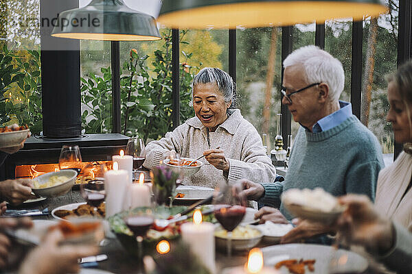 Ältere Frau serviert einem männlichen Freund bei einer Dinnerparty Essen
