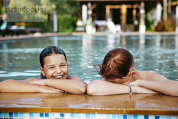 Glückliches Mädchen mit Bruder im Schwimmbad im Urlaub genießen