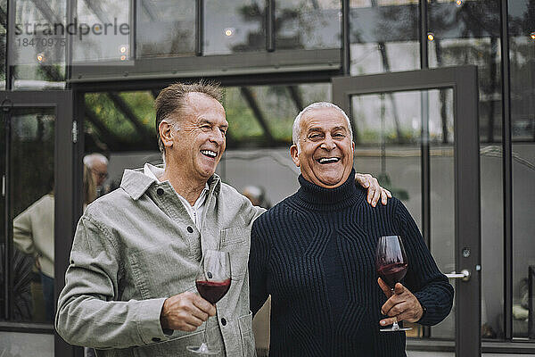Glückliche männliche Freunde im Ruhestand mit Wein bei einer Dinnerparty