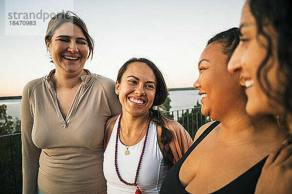 Multirassische glückliche Freundinnen  die bei Sonnenuntergang zusammen lachen