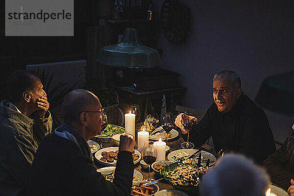 Männliche Freunde  die während einer nächtlichen Dinnerparty miteinander reden
