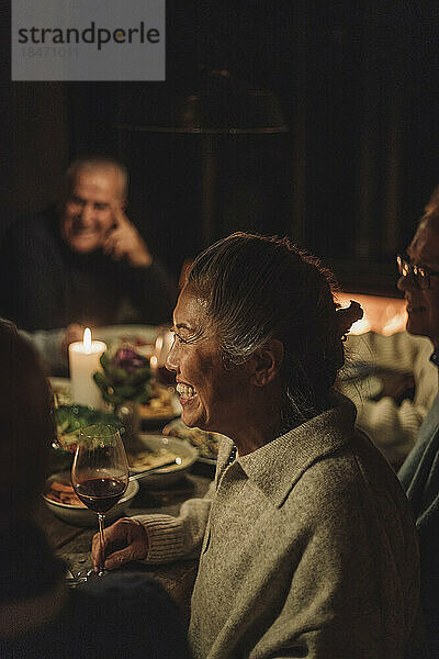 Seitenansicht einer glücklichen älteren Frau  die ein Abendessen bei Kerzenschein genießt
