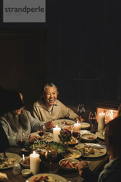 Glückliche ältere Frau mit Freunden  die das Essen auf einer Dinnerparty genießen