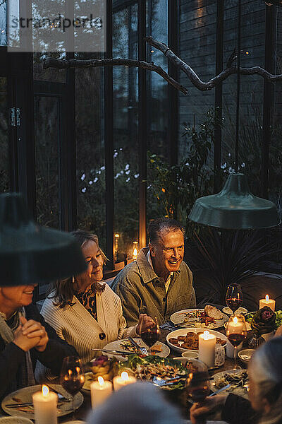 Glückliche ältere männliche und weibliche Freunde beim Essen auf einer Dinnerparty