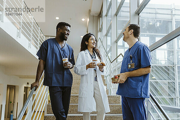 Glückliches multirassisches Gesundheitspersonal im Gespräch auf einer Treppe im Krankenhaus