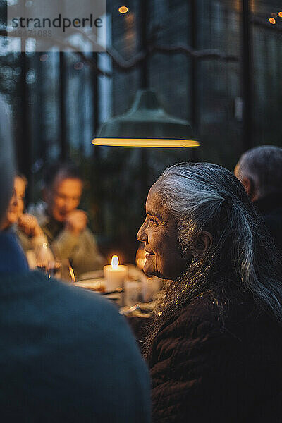 Ältere Frau inmitten von Freunden bei einer Dinnerparty