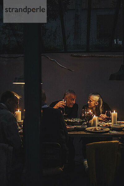 Mann und Frau unterhalten sich während einer nächtlichen Dinnerparty miteinander