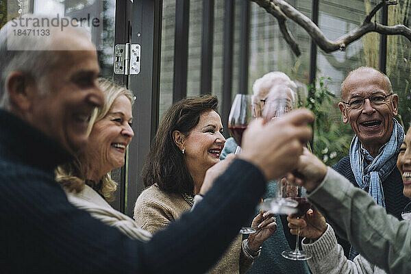 Fröhliche männliche und weibliche Freunde im Ruhestand stoßen bei einer Dinnerparty auf Getränke an