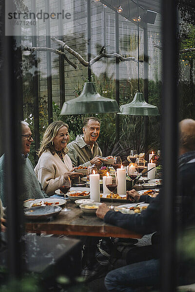 Ein Mann und eine Frau im Ruhestand genießen ein gemeinsames Abendessen  gesehen durch Glas