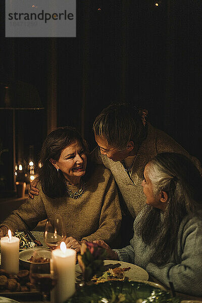 Ältere Frau im Gespräch mit Freundinnen beim Candlelight-Dinner