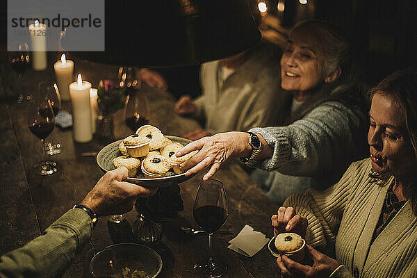 Ältere Frau  die während einer Dinnerparty ein Törtchen vom Teller nimmt