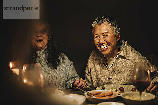 Glückliche ältere Frau  die bei einer Dinnerparty mit ihrer Freundin lacht