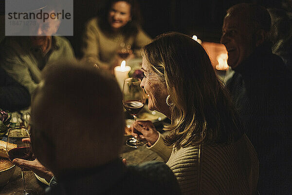 Lächelnde ältere Frau genießt mit männlichen und weiblichen Freunden bei Kerzenlicht Abendessen Partei
