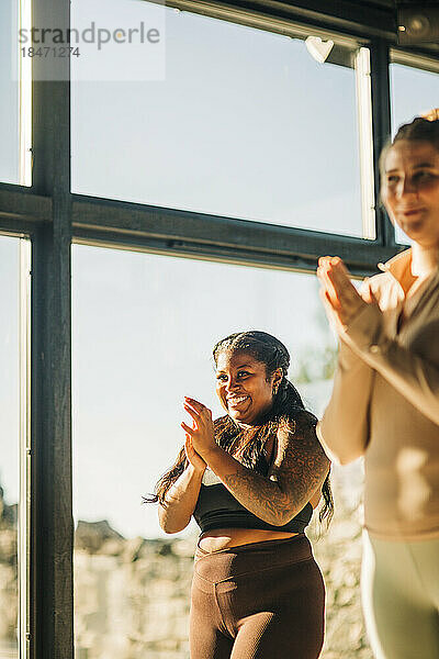 Glückliche Frauen klatschen während einer Yogastunde im Retreat Center