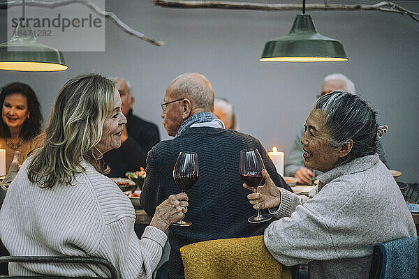 Ältere Frauen mit Weingläsern  die sich bei einer Dinnerparty unterhalten