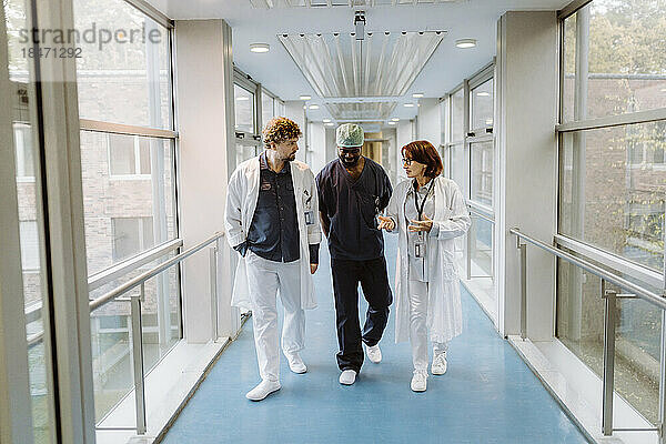 Oberärztin in voller Länge im Gespräch mit Kollegen auf einem Krankenhausflur