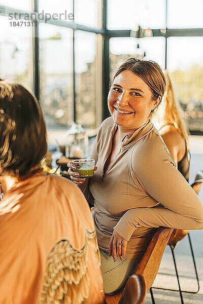 Porträt einer lächelnden Frau  die auf einem Stuhl sitzt  während sie im Exerzitienhaus frühstückt