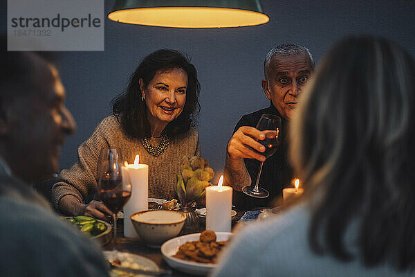 Lächelnde Frau im Ruhestand genießt das Abendessen mit Freunden auf einer Party