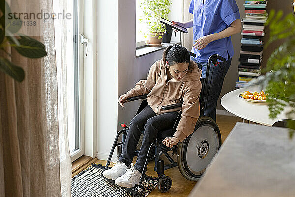 Frau mit Querschnittslähmung passt Rollstuhl zu Hause an
