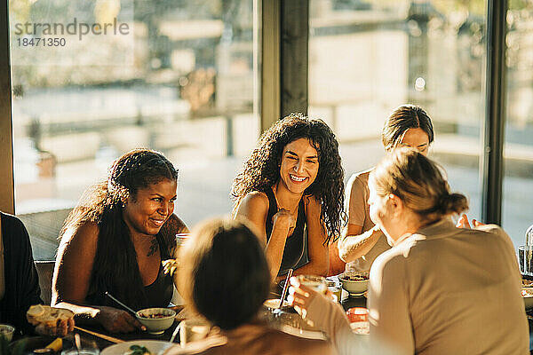 Fröhliche Freundinnen lachen beim gemeinsamen Frühstück im Exerzitienhaus