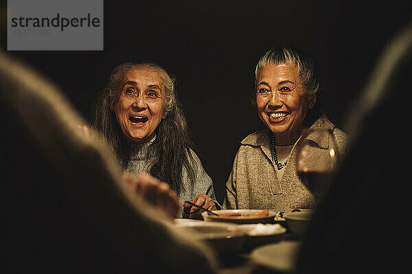 Glückliche ältere weibliche Freunde während einer nächtlichen Dinnerparty