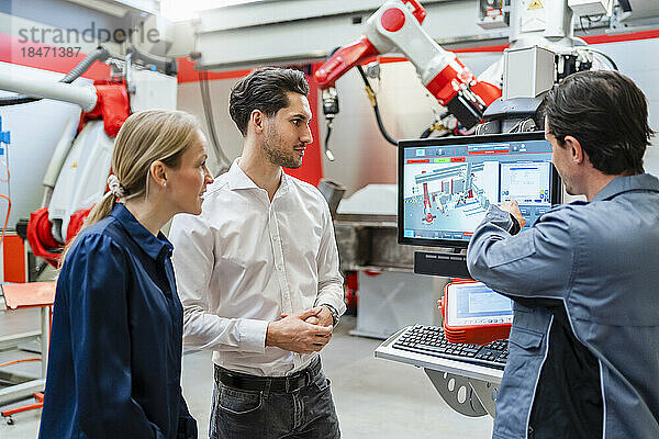 Ingenieur erklärt Kollegen über Monitor in Roboterfabrik
