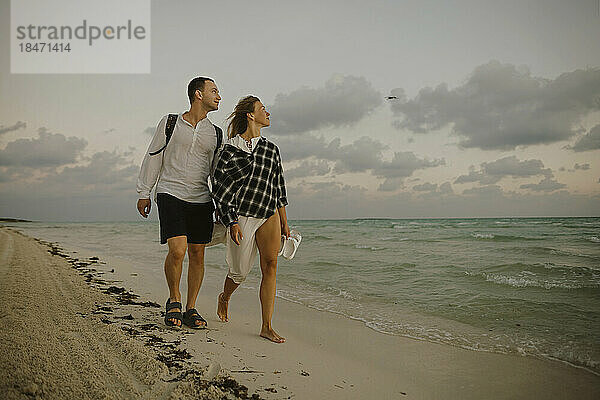 Mann und Frau gehen gemeinsam am Strand in Ufernähe spazieren