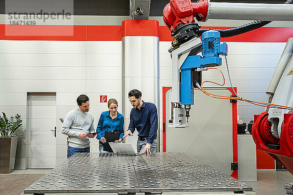 Kollegen arbeiten am Laptop in der Roboterfabrik zusammen