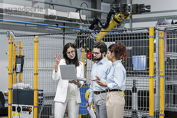 Geschäftsfrau diskutiert am Laptop mit Kollegen in der Fabrik