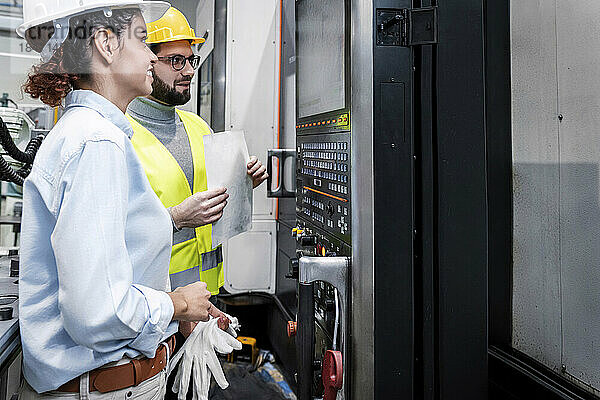 Lächelnde Ingenieure blicken auf den Bedienfeldbildschirm in der Fabrik