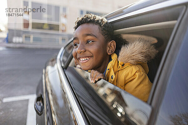 Fröhlicher Junge  der aus dem Autofenster schaut