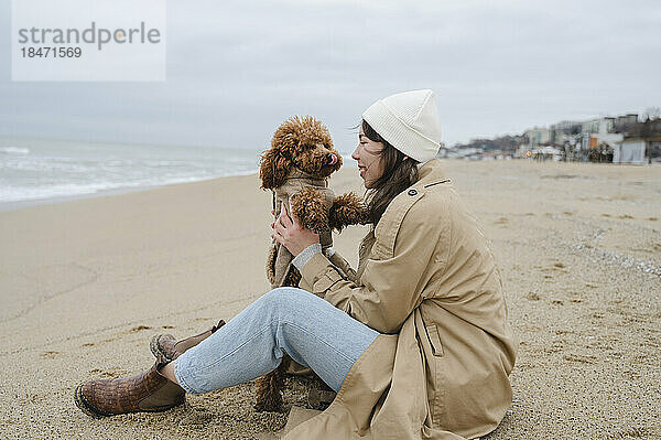 Woman enjoying with pet dog sitting at beach