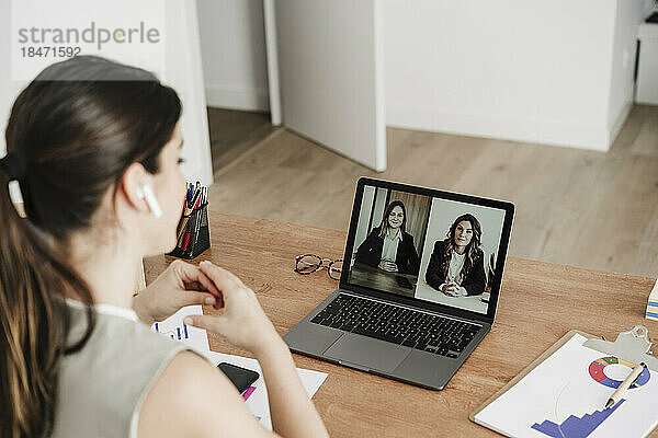 Businesswoman on video call with colleagues discussing through laptop in office