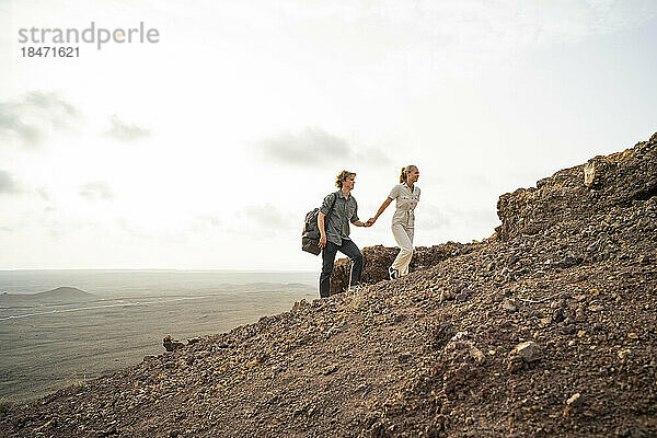 Junges Paar hält Händchen und wandert auf dem Berg
