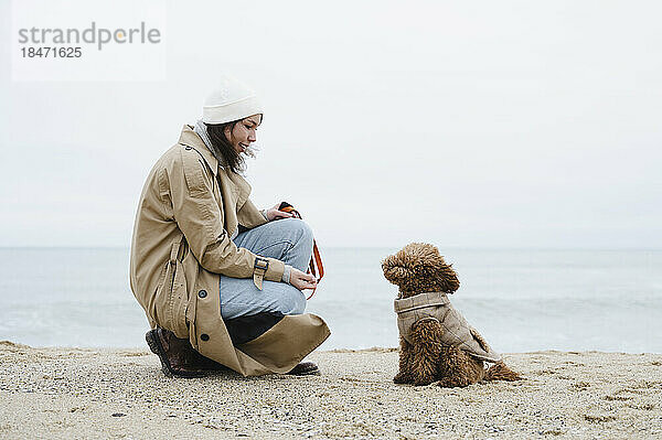 Young woman crouching by dog at beach