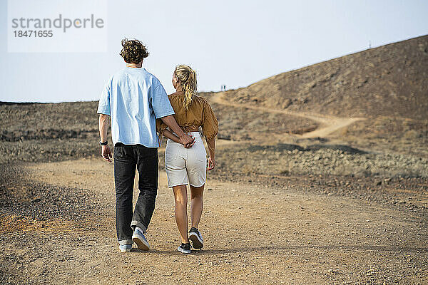Freund und Freundin gehen miteinander auf unbefestigter Straße spazieren
